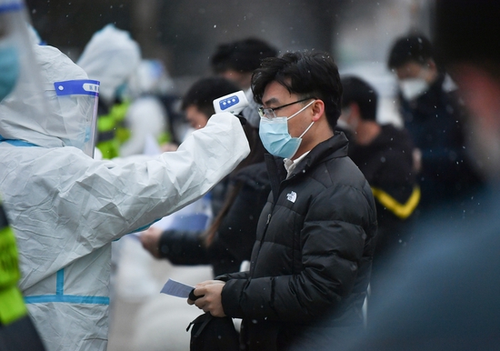 12月25日,在西安交通大学城市学院考点,工作人员为考生测温.