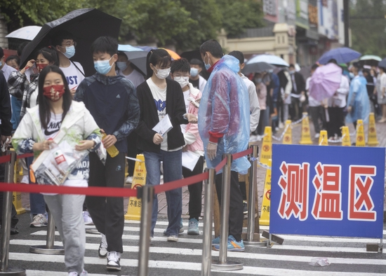 ▲6月25日，在哈尔滨市第七十二中学考点，考生测温后进入考场。图/新华社