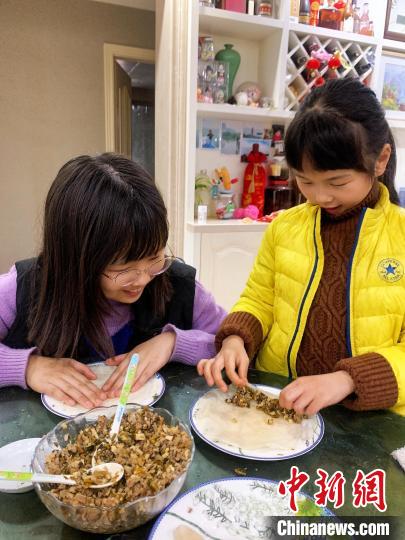 学生在家长陪伴下包馅饼。　李茜 供图