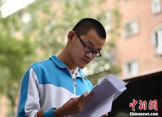 资料图：北京丰台二中高考考点，一名考生进入考场前复习考试资料。中新社记者 张兴龙 摄