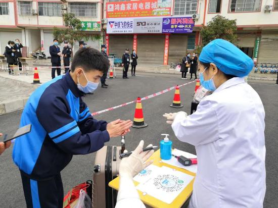 册亨民族中学，学生进校门前进行手部消毒