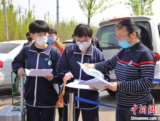 图为返校学生在校门口向老师交健康登记卡和山东省健康通行码。 赵晓 摄