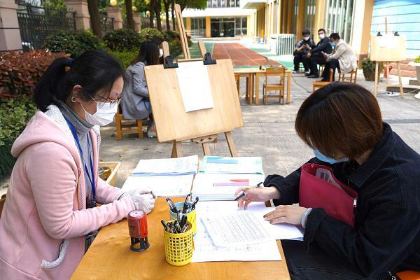 图说：杨浦区本溪路幼儿园信息登记现场预约的家长在老师的指导下完成信息填写