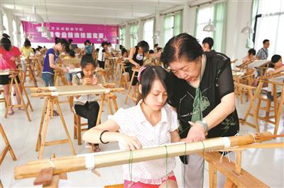 湘绣大师刘爱云（右）在湖南工艺美术职院指导学生。资料图片