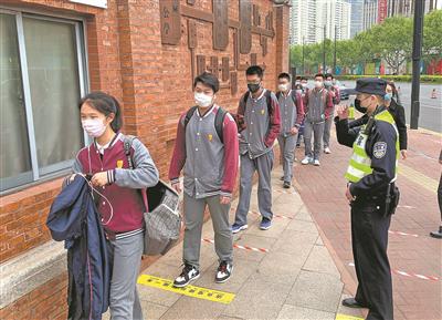 4月27日,上海市公安局徐汇分局徐家汇派出所的民警赵喆在徐汇中学校门外提醒入校学生保持一米距离。当日,上海高三年级、初三年级学生返校开学。新华社记者 凡军 摄