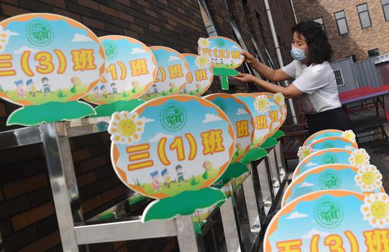 8月24日，北京教育学院附属丰台实验学校，一名教师在摆放学生错峰放学标牌。