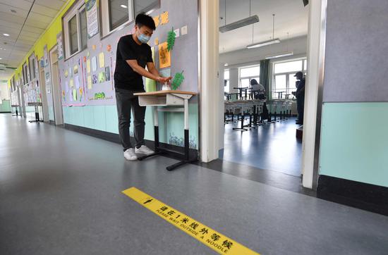 8月24日，北京教育学院附属丰台实验学校，一名教师在教室外码放手部消毒液。