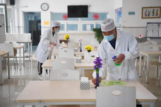 8月24日，北京教育学院附属丰台实验学校，食堂工作人员在对饭桌进行消毒。