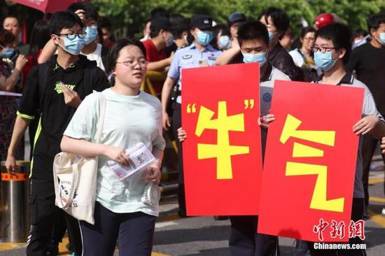 6月7日，江苏省南京市雨花台中学高考考点前，高二的学生手举“牛气冲天”“牛转乾坤”字样为考生加油鼓劲。 中新社记者 泱波 摄