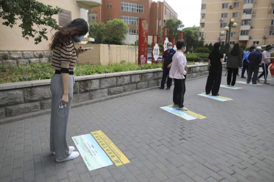 ▲5月5日，海淀区羊坊店街道莲花小区，一位女士在排队时拍摄地上的古诗。 新京报记者 浦峰 摄
