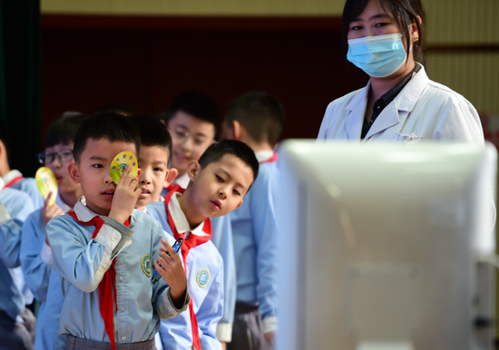   2021年3月22日，在河北沧州市实验小学，医生志愿者指导学生进行裸眼视力检查。新华社发（傅新春 摄）