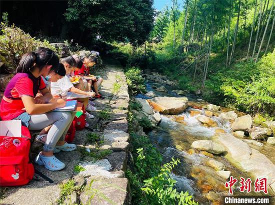 图为孩子们在山间溪水旁写生作画。李明明摄