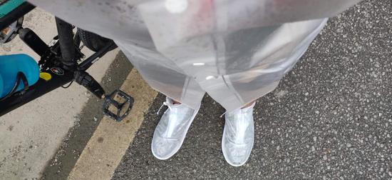 路上下雨，叶志加了件雨衣鞋套。受访者供图