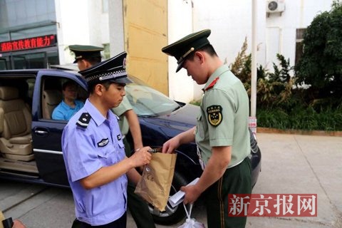 执勤的武警战士将用于执勤时联系部队的通讯设备交给了印刷厂的工作人员，随后他们将随各个考点的车辆进入库区请领试卷。
