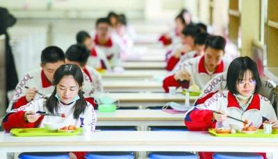 同学们在食堂保持一定间隔吃午饭。