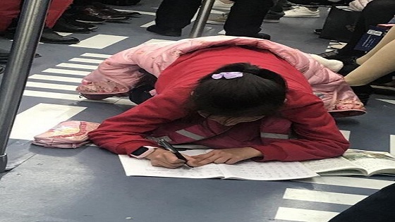 女孩地铁上趴地专心写作业 姿势让人心疼