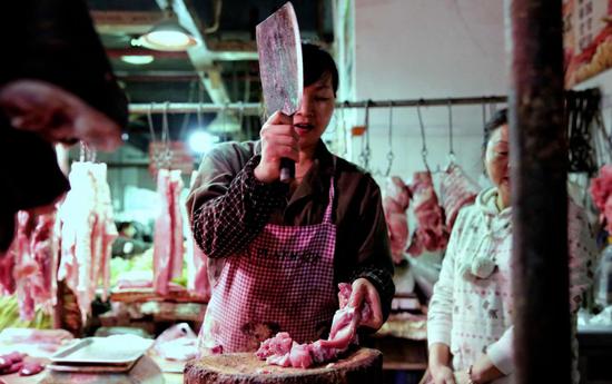 猪肉铺中,老板娘正在剁肉.图/图虫·创意