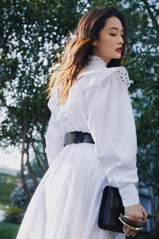 照片中,李沁身穿复古镂空蕾丝白色长裙,妆容精致,长发垂肩.