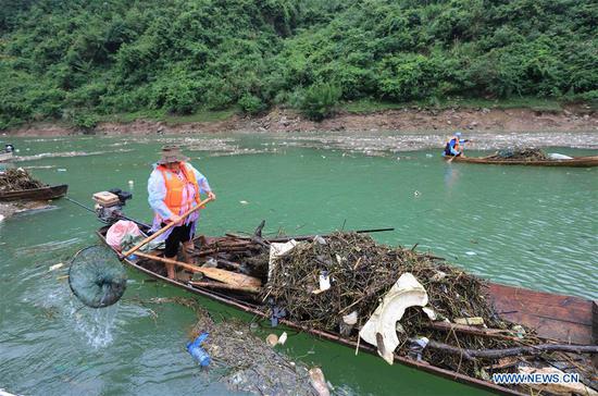 A villager clears up flotage from Maoyan River in Yongding District of Zhangjiajie City, central China's Hunan Province, Sept. 6, 2020. The city has organized people to regularly clear up flotage on the river to keep the riverway unimpeded. (Photo by Wu Yongbing/Xinhua)