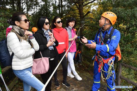 A member of Zhangjiajie Blue Sky rescue team introduces knowledge of environmental protection to tourists at Huangshizhai scenic spot in Zhangjiajie, central China's Hunan Province, Oct. 21, 2020. The Blue Sky rescue team, formed by local volunteers, often pick garbage during their practice at the scenic area, calling on tourists here to protect the environment. (Xinhua/Zhao Zhongzhi)