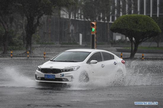 A car runs in the rain in Haikou, south China's Hainan Province, Oct. 28, 2020. Molave weakened from a super typhoon to typhoon on Wednesday morning, bringing rainstorms to the island province of Hainan in south China, the local weather bureau said. (Xinhua/Pu Xiaoxu)