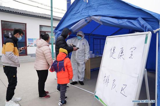 A medical worker (1st, R) scans to register personal information at a sampling site in Shunyi District of Beijing, capital of China, Dec. 28, 2020. Beijing has expanded its nucleic acid testing and tightened COVID-19 prevention and control measures following new reports of local COVID-19 infections, local authorities said on Monday. (Xinhua/Ju Huanzong)