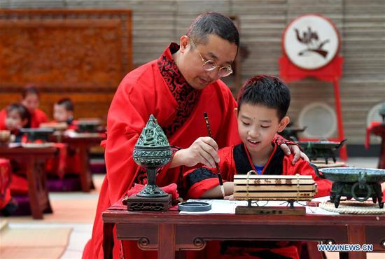 A boy and his parent attend the First Writing Ceremony, a traditional activity held for children before they are admitted to school, at a museum in Xi'an, northwest China's Shaanxi Province, Sept. 13, 2020. (Xinhua/Liu Xiao)