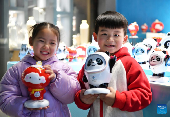 Two kids show their newly-bought porcelain figures of Beijing 2022 mascots at a porcelain factory in Dehua County of Quanzhou, southeast China's Fujian Province, Jan. 19, 2022. (Xinhua/Wei Peiquan)