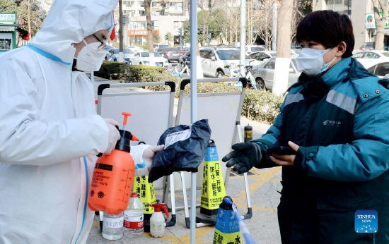 A volunteer disinfects a parcel to be delivered to a resident in Xi'an, capital of northwest China's Shaanxi Province, Jan. 13, 2022. Postal and express delivery services in Xi'an have been gradually resumed in an orderly manner with strengthened epidemic prevention measures amid the latest resurgence. (Photo by Zou Jingyi/Xinhua)