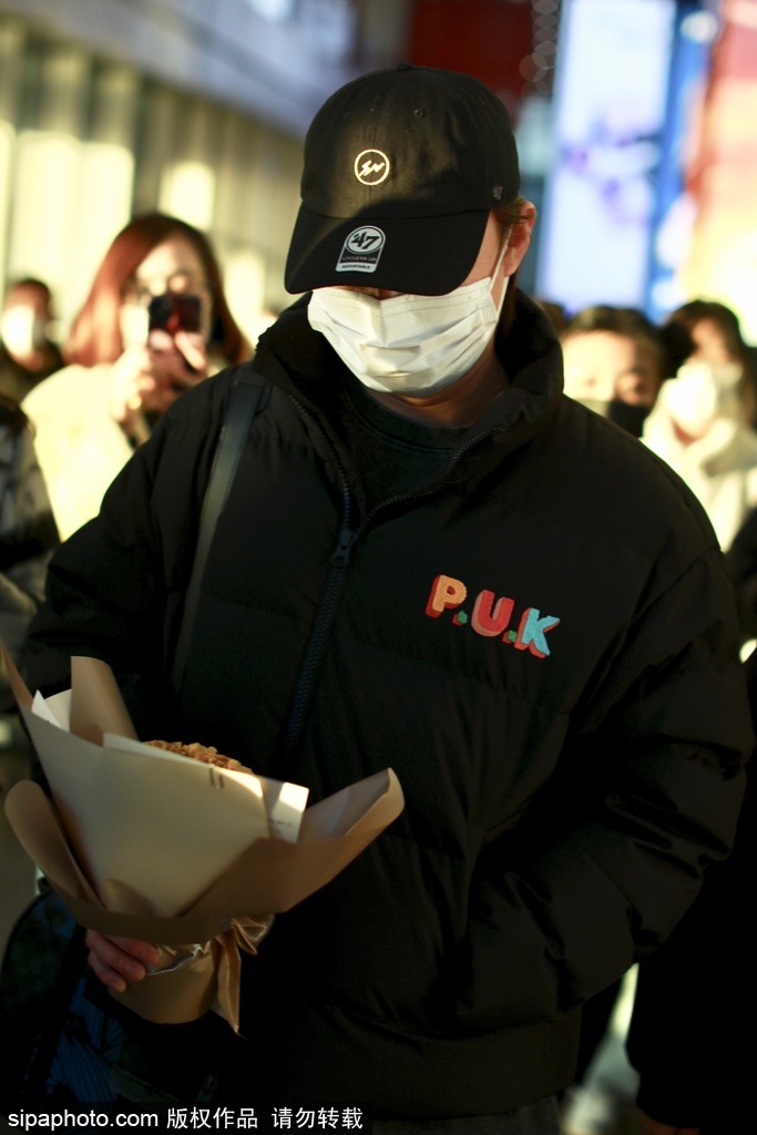 组图：尹正穿黑色羽绒夹克酷拽现身机场 收粉丝花束心情大好