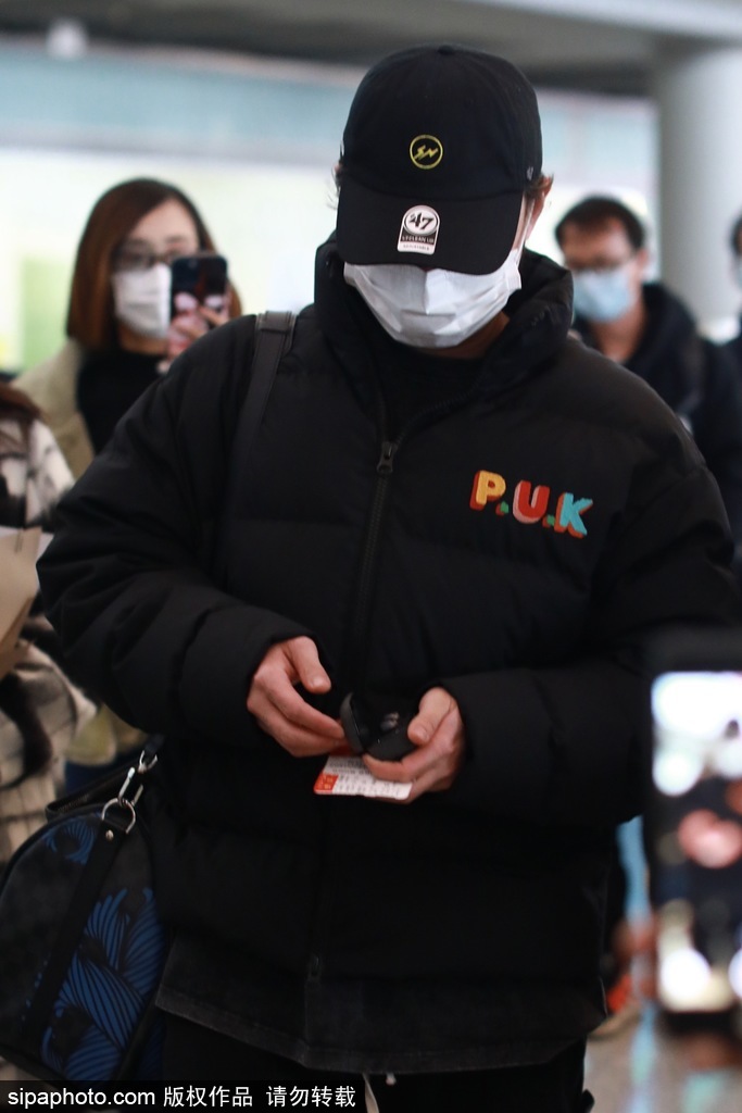组图：尹正穿黑色羽绒夹克酷拽现身机场 收粉丝花束心情大好