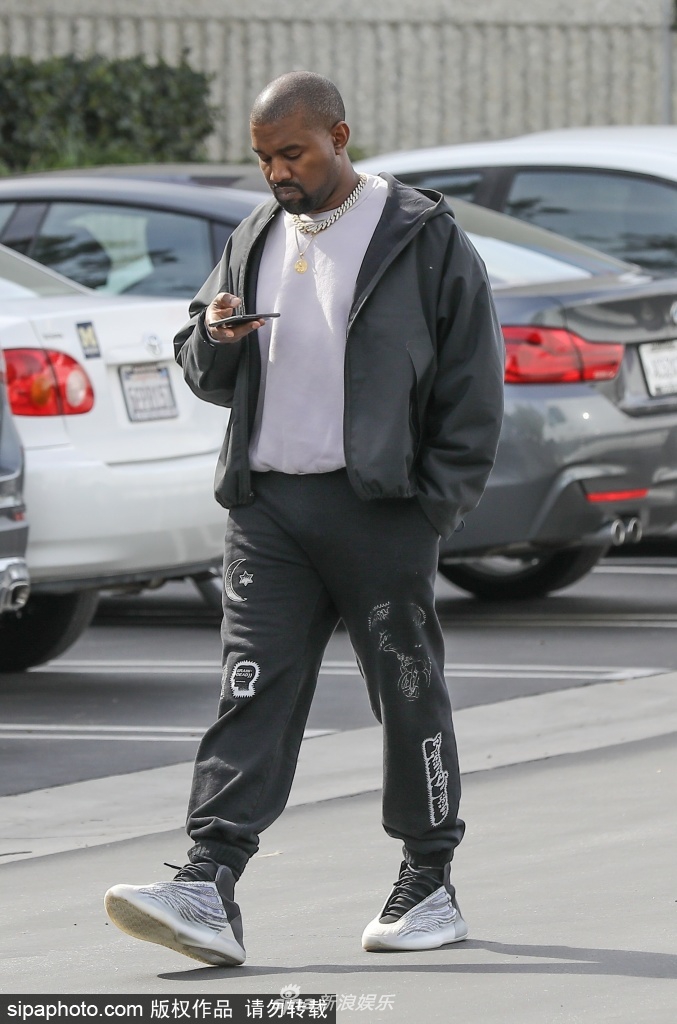 组图: "侃爷"穿潮鞋街头出镜 一路看手机成低头族