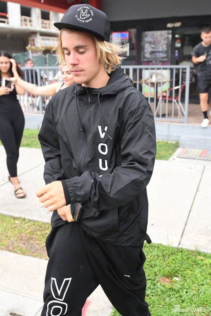 bieber最新街拍出炉,他一身黑色运动服,头戴棒球帽,一头金色长发乱糟