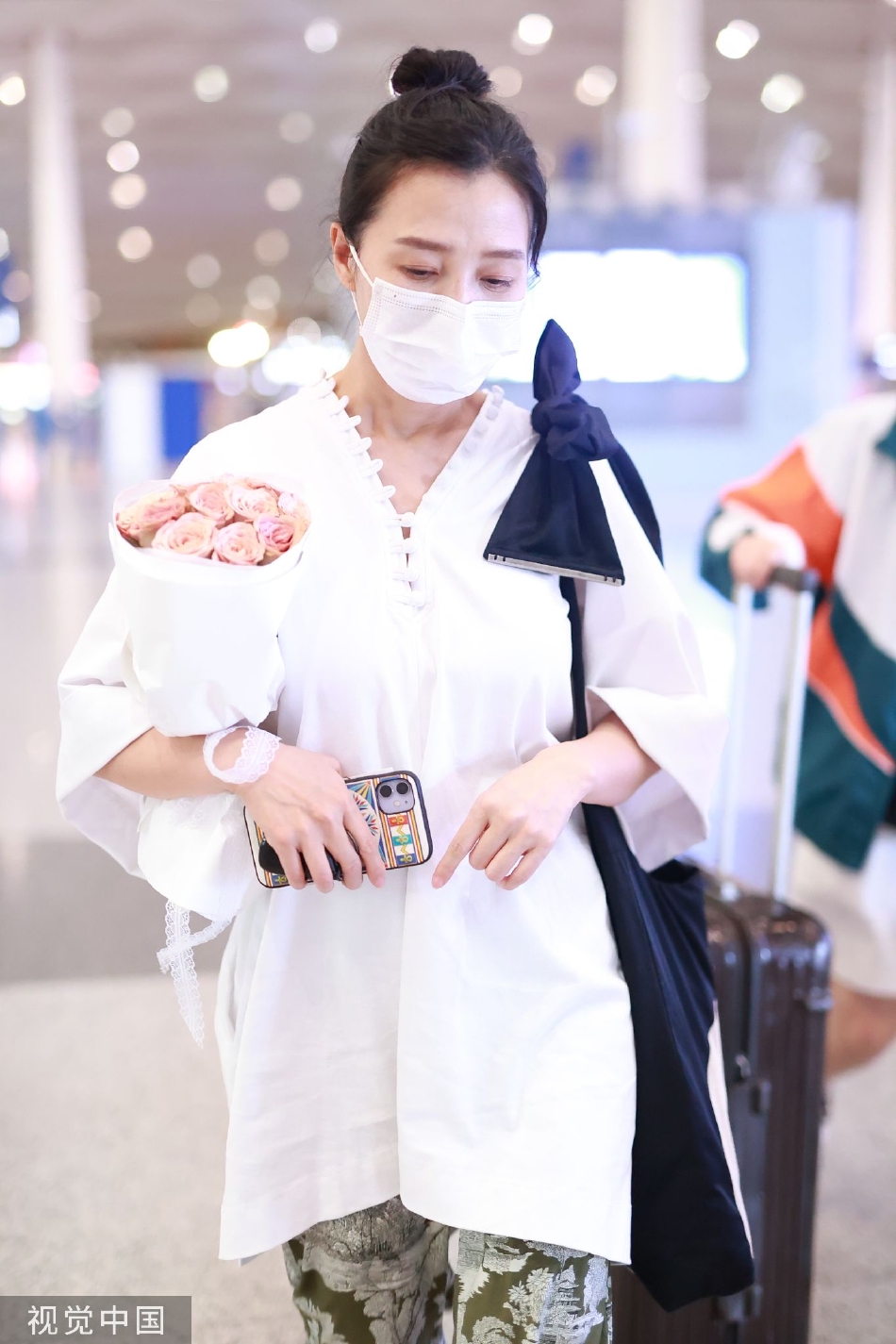 组图:阿朵手捧鲜花现身机场 扎着丸子头休闲随性