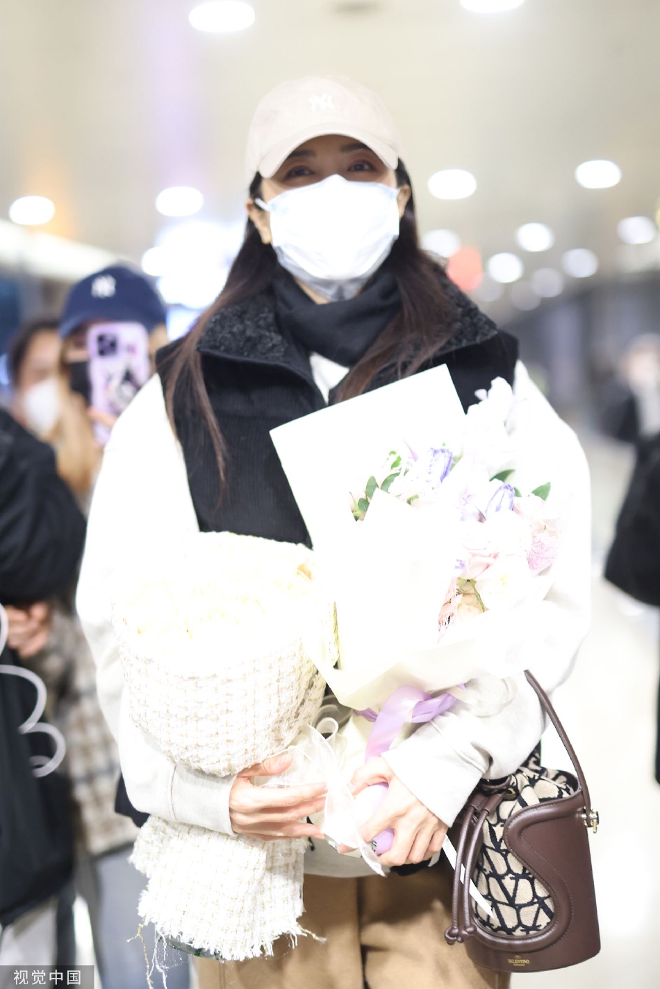 组图：曾黎穿白色卫衣配马甲现身机场 获粉丝赠花面带灿笑气质好