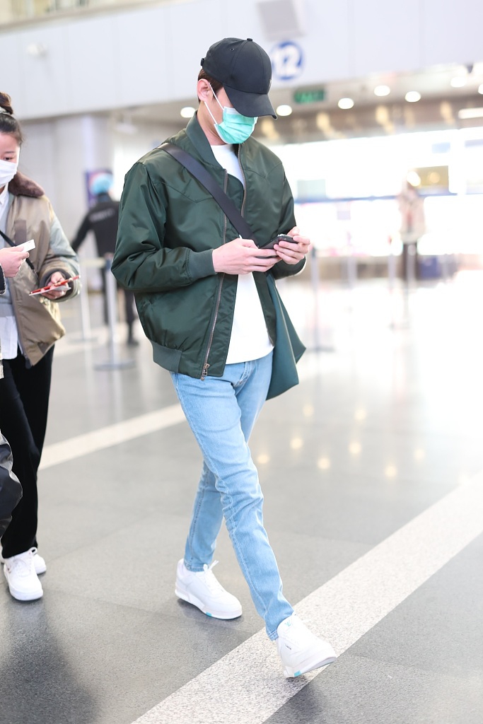 组图:王凯穿绿色飞行夹克现身机场 赶路不时低头看手机