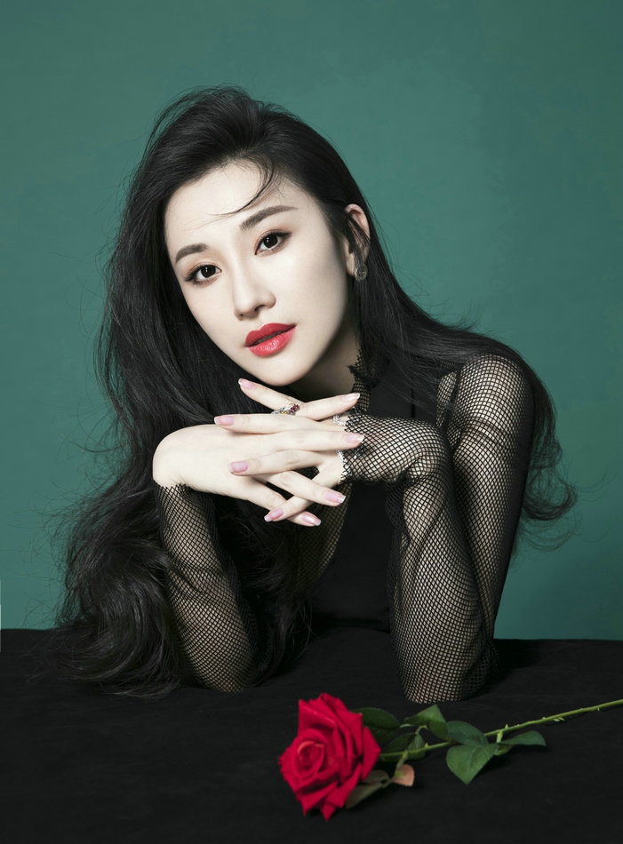 写真中朱子岩身着黑色连衣裙,渔网袖,红玫瑰的绝美搭配尽显风情,眉宇