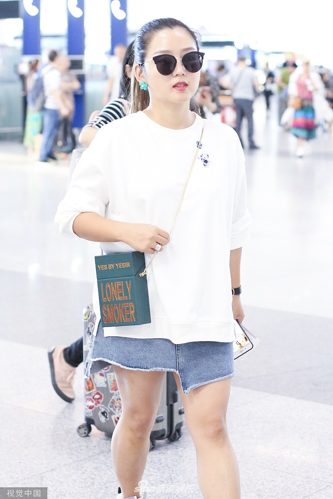 组图:何洁穿牛仔短裙自信秀腿 梳马尾辫戴花朵耳环和粉丝自拍