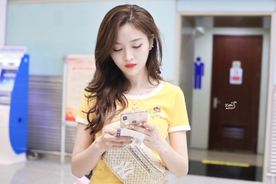 组图：吴宣仪着清新黄T现身机场 双手向上伸懒腰表情显疲惫