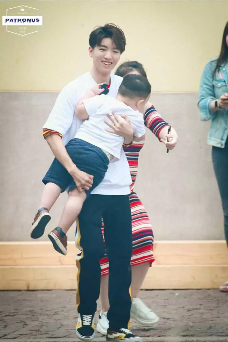 双手抱着一个小朋友,看样子小朋友的重量似乎有些难以承受,王俊凯像是