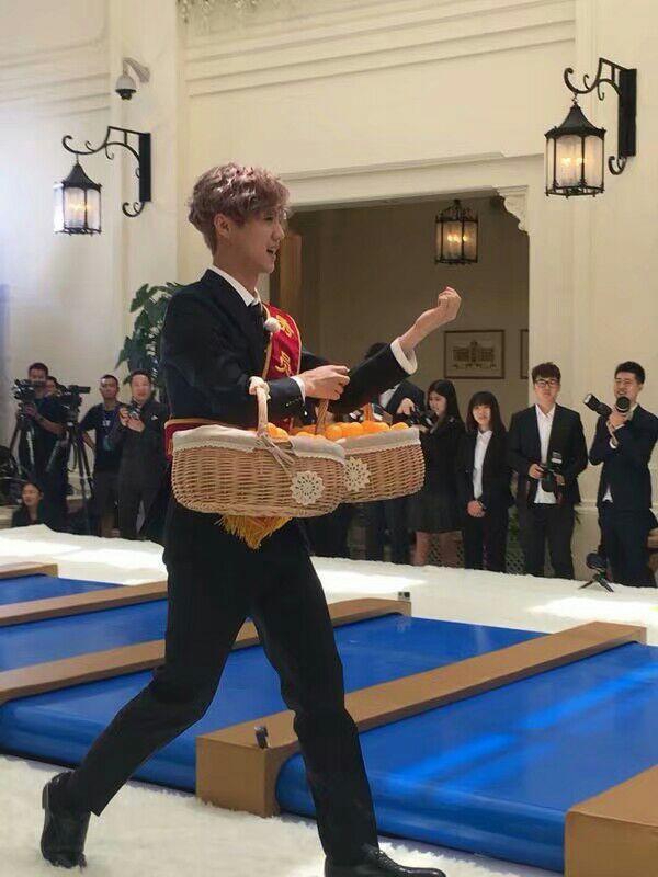 鹿晗穿黑色西装身上挂着"优秀员工"的绶带,胳膊上挎两篮子乒乓球,画面