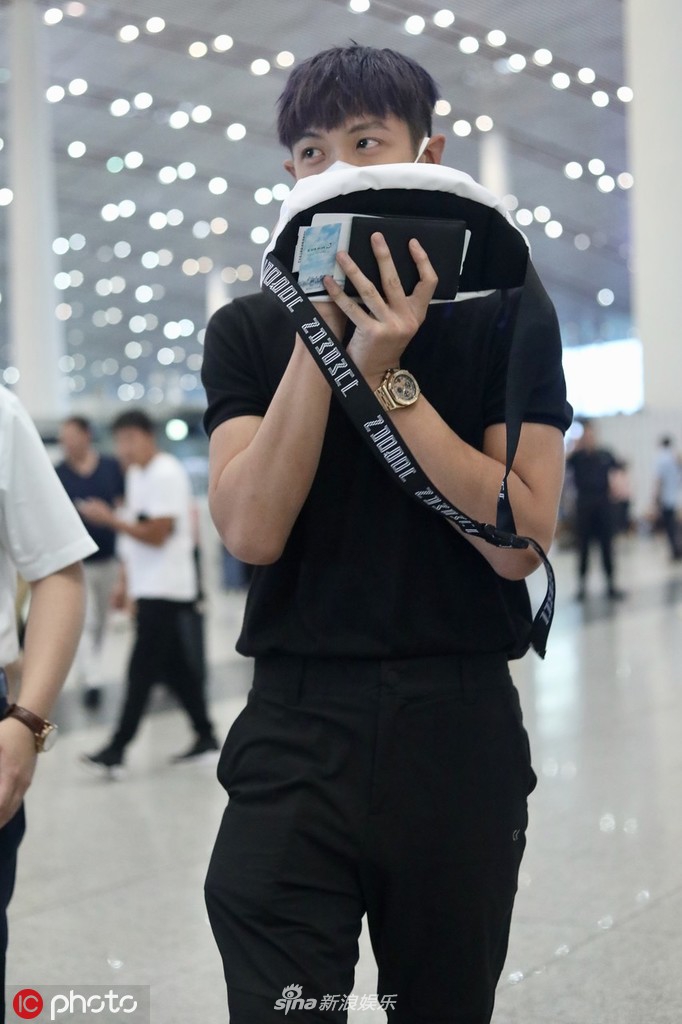 组图柯震东现身机场用包挡脸换新发型肤色黑不少