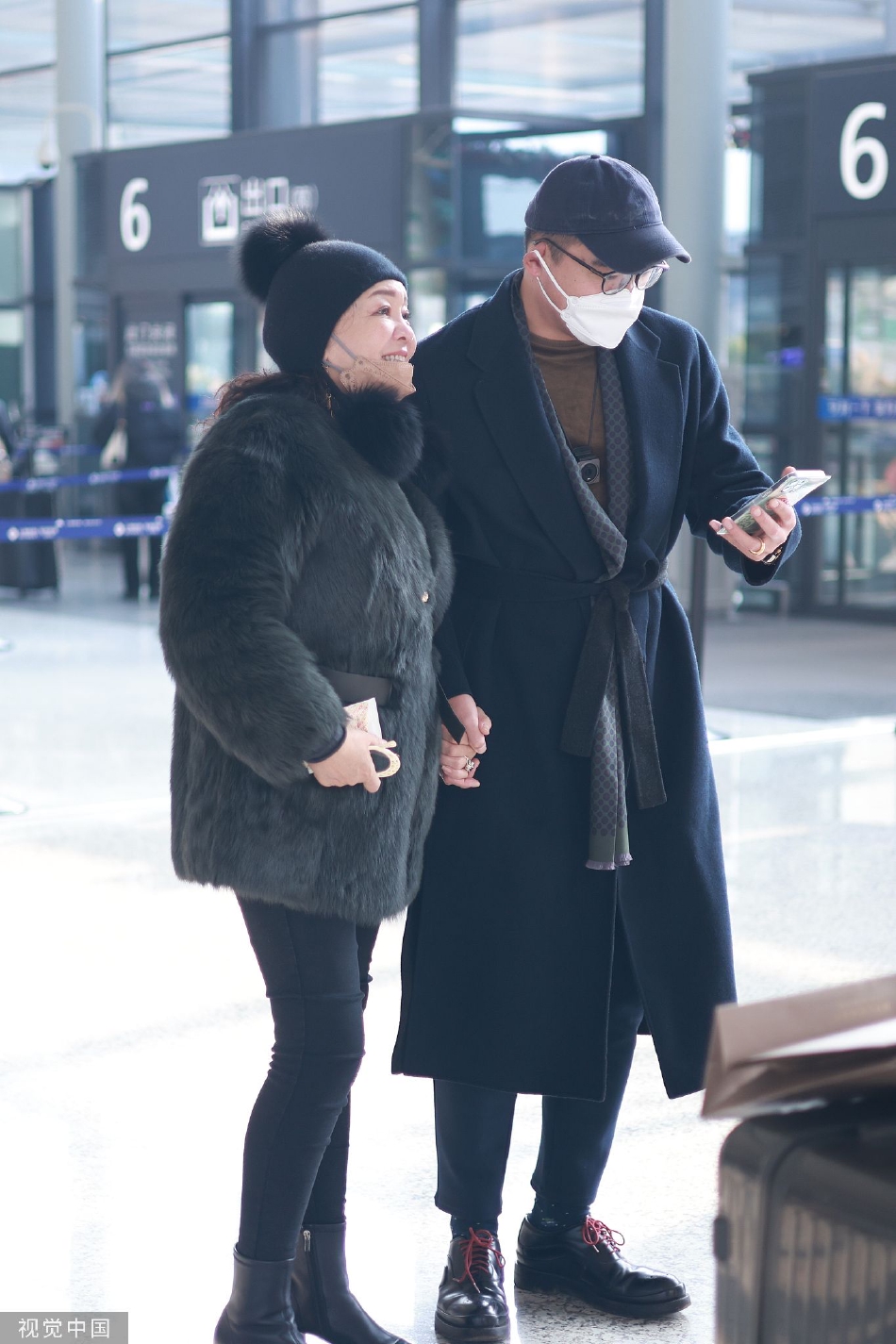 组图：张兰穿黑色毛绒外套现身机场 戴针织帽面带灿笑气色好