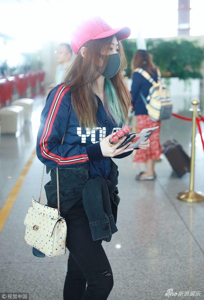 张靓颖戴小红帽赶早班机 戴口罩一路低头玩手机