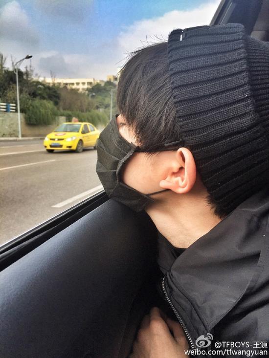 照片中,王源戴着黑色帽子和黑色口罩,将脸贴近车窗,闭上眼睛露出侧颜.