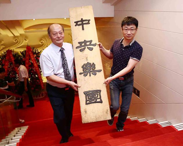 关峡、李心草抬着“中央乐团”的牌匾步入图片展厅