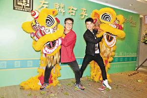 谭咏麟(左)和李克勤齐举狮头,为名下的餐馆卖力娱宾。