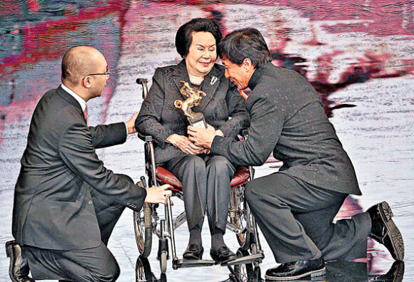 在前年金马奖，成龙(右)以单膝下跪颁奖给李丽华(中)。