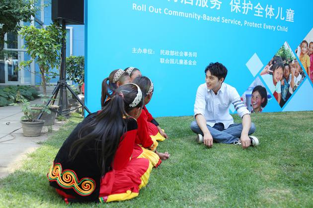 许魏洲和小朋友坐在草地上聊天