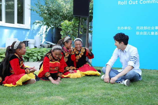 许魏洲和小朋友坐在草地上聊天